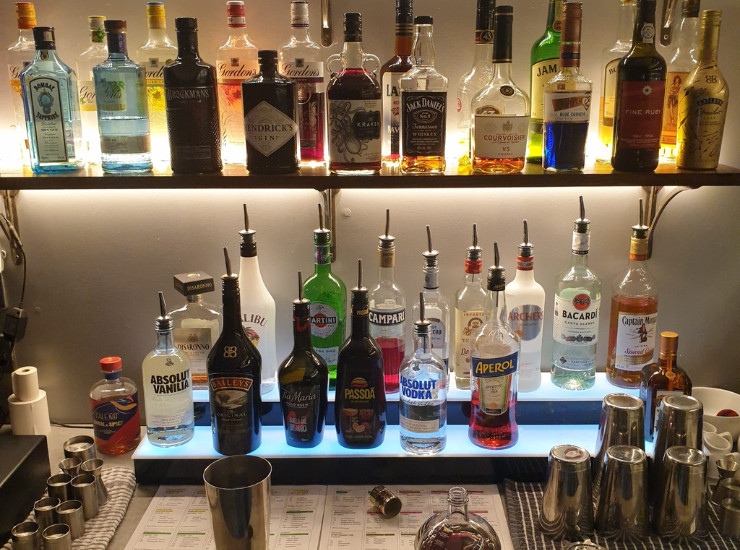 Variety of alcoholic spirits on a shelf with cocktail shakers and drink measures